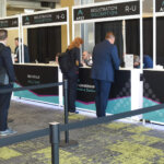 Executives lining up in front of registration booths at the APEX summit 2023